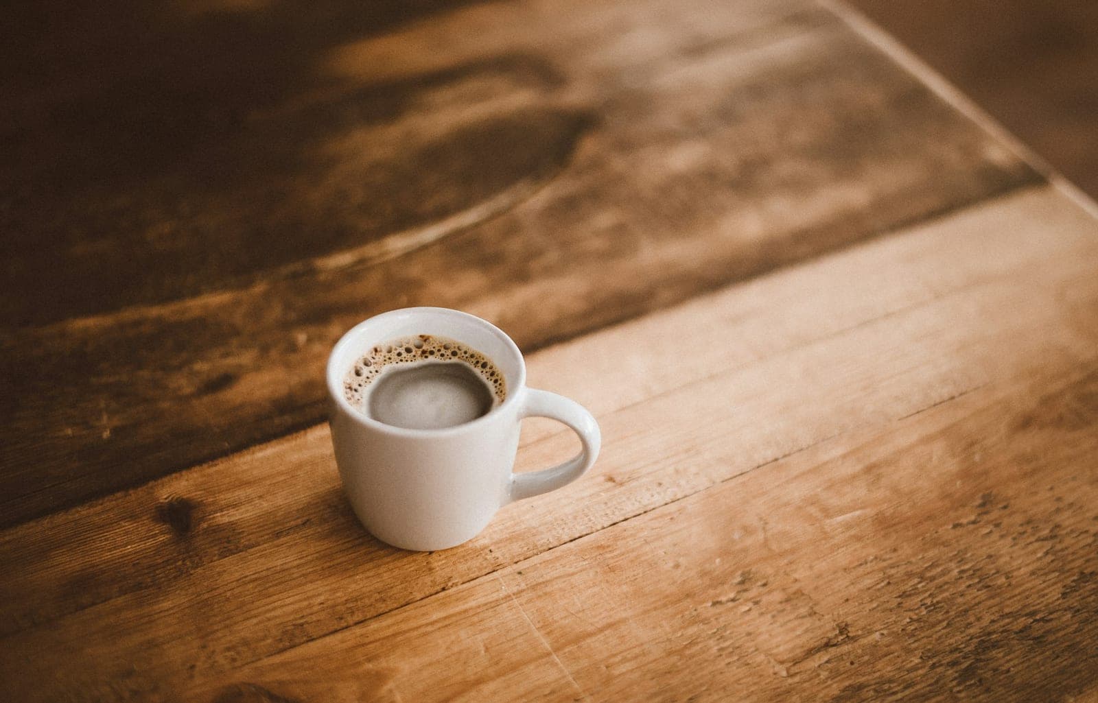 Forge Mug – vit keramikmugg med kaffe på varmt träbord
